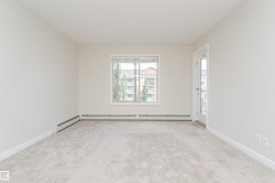 Spacious room featuring light-toned carpet, neutral wall paint, and white trim - 