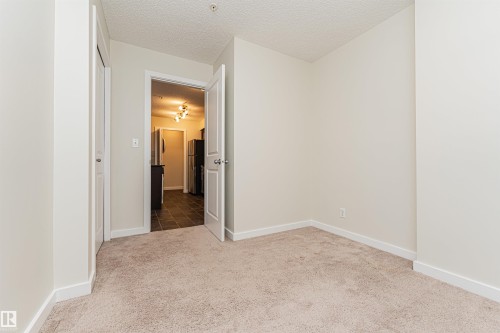 Carpeted interior space featuring light-colored walls and white trim - #322 5816 Mullen Pl Nw, Edmonton, AB - Indoor Photo Showing Other Room