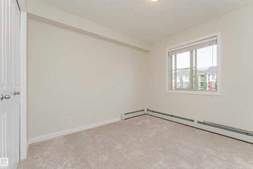 Carpeted interior room with neutral wall tones - #322 5816 Mullen Pl Nw, Edmonton, AB - Indoor Photo Showing Other Room