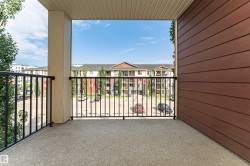 Private balcony featuring a textured concrete surface, black metal railings, and a solid exterior wall with horizontal brown siding - 
