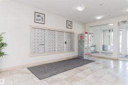 Lobby area featuring light-toned tile flooring, recessed wall-mounted mailboxes, and glass entry doors - 