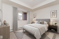 Bedroom featuring light-colored walls, a tray ceiling, and a large window with blinds and drapes - 