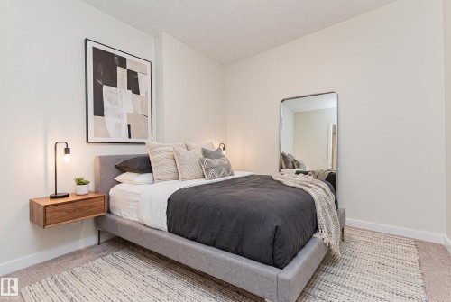 Neutral wall paint with carpet flooring - #322 5816 Mullen Pl Nw, Edmonton, AB - Indoor Photo Showing Bedroom