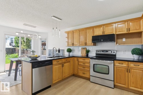 Kitchen featuring light wood cabinetry, dark countertops, and stainless steel appliances - 64 Foxboro Link, Sherwood Park, AB - Indoor Photo Showing Kitchen