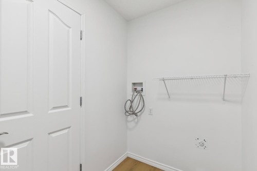 Dedicated laundry area featuring a white wire shelf, water hookups, and wood-finish flooring - 64 Foxboro Link, Sherwood Park, AB - Indoor