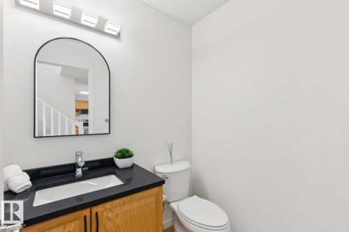 Powder room featuring a wood-finish vanity with a black countertop and an integrated white rectangular sink - 64 Foxboro Link, Sherwood Park, AB - Indoor Photo Showing Bathroom