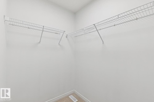 Walk-in closet with white wire shelving, light-colored carpeting, and white baseboards - 64 Foxboro Link, Sherwood Park, AB - Indoor With Storage
