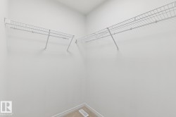 Walk-in closet with white wire shelving, light-colored carpeting, and white baseboards - 