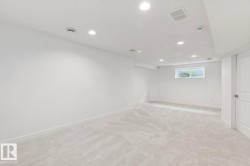 Spacious room featuring light-toned carpeting, recessed lighting, and a white paneled door - 