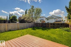 Expansive backyard featuring a large wood deck, manicured lawn, and perimeter wood fencing - 