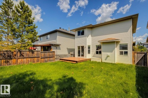 Spacious backyard featuring a wooden privacy fence, a ground-level wood-finish deck, and a contemporary light-colored siding exterior - 64 Foxboro Link, Sherwood Park, AB - Outdoor