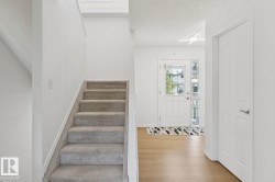 Foyer featuring wood-finish flooring and a white paneled entry door with sidelight - 