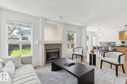 Living area featuring a gas fireplace with tile surround, adjacent windows, and wood-finish flooring - 