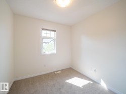 Windowed room featuring neutral-toned walls, plush carpeting, and white baseboards - 