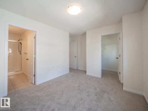 Spacious room featuring neutral carpet flooring, recessed lighting, and access to a full bathroom with a stand-up shower - #66 465 Hemingway Rd Nw, Edmonton, AB - Indoor