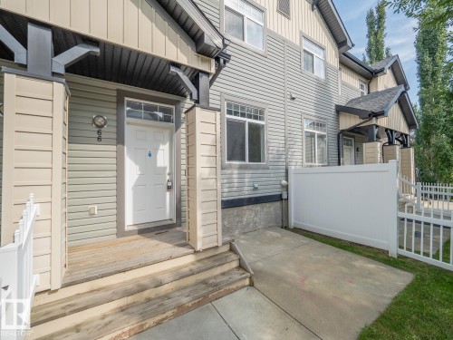 Multi-story exterior featuring tan and grey siding, a white entry door with transom window, and a covered porch with dark wood accents - #66 465 Hemingway Rd Nw, Edmonton, AB - Outdoor With Exterior