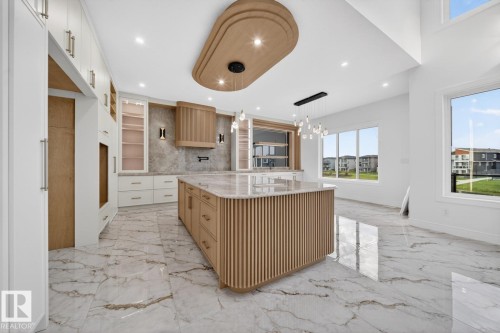 Kitchen featuring a slatted wood-finish island with stone countertop, integrated wood-finish paneled appliances, and ample white cabinetry - 11 Harley Way, Spruce Grove, AB - Indoor Photo Showing Kitchen