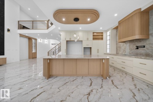 Open-concept kitchen featuring an expansive center island with a light wood-finish base, integrated cabinetry, and stone countertop - 11 Harley Way, Spruce Grove, AB - Indoor Photo Showing Kitchen