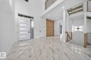 Two-story foyer featuring large format marble-look tile flooring, a modern entry door with frosted glass panels and transom window, and a wood-finish staircase with contemporary black metal railings - 11 Harley Way, Spruce Grove, AB  - Indoor Photo Showing Other Room 