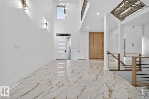 Spacious entryway featuring high ceilings, large format marble-look tile flooring, and a modern chandelier - 11 Harley Way, Spruce Grove, AB - Indoor Photo Showing Other Room