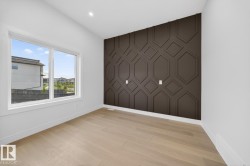 Accent wall with geometric paneling and light wood-finish flooring - 