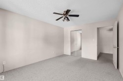 Bedroom featuring light grey carpeting, white walls, and a textured white ceiling - 