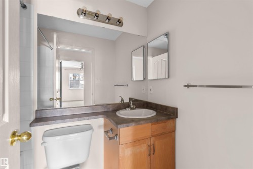 Bathroom featuring a light wood-finish vanity with a built-in sink, an extended countertop, and a large wall-mounted mirror - #224 16303 95 St Nw, Edmonton, AB - Indoor Photo Showing Bathroom