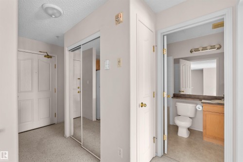 Entryway featuring textured carpeting and a mirrored closet door - #224 16303 95 St Nw, Edmonton, AB - Indoor Photo Showing Bathroom