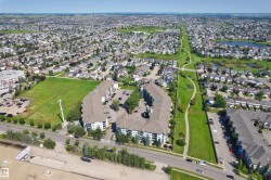 Expansive residential area featuring a large undeveloped green space, a multi-building apartment complex with parking, and a paved roadway - 