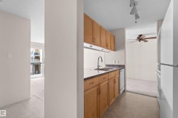 Functional kitchen featuring wood cabinetry, laminate countertops, a stainless steel sink, and a white dishwasher - 
