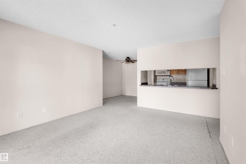 Open-concept living area featuring light-colored carpeting and neutral wall tones - #224 16303 95 St Nw, Edmonton, AB - Indoor Photo Showing Other Room