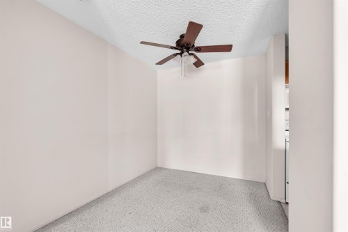 Room featuring a ceiling fan with integrated lighting, textured white ceiling, light neutral-toned walls, and grey carpet flooring - #224 16303 95 St Nw, Edmonton, AB - Indoor Photo Showing Other Room