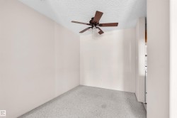 Room featuring a ceiling fan with integrated lighting, textured white ceiling, light neutral-toned walls, and grey carpet flooring - 