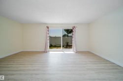 Spacious interior room featuring light-colored walls and wood-finish flooring - 
