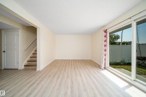 Spacious interior with wood-finish flooring, a white trim baseboard, and light-toned walls - 11432 139 Avenue Nw, Edmonton, AB - Indoor Photo Showing Other Room
