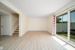 Spacious interior with wood-finish flooring, a white trim baseboard, and light-toned walls - 