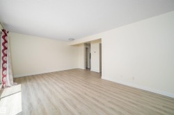 Spacious living area featuring light wood-finish flooring and neutral-toned walls - 
