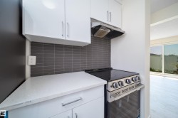 Modern kitchen featuring white cabinetry, a light-toned countertop, and a dark subway tile backsplash - 