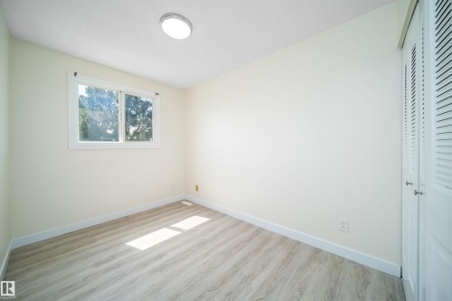 Bright interior space featuring light wood-finish flooring, white baseboards, and a large window with white trim - 11432 139 Avenue Nw, Edmonton, AB - Indoor Photo Showing Other Room