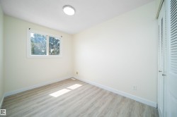Bright interior space featuring light wood-finish flooring, white baseboards, and a large window with white trim - 
