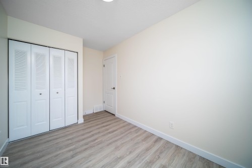 Interior room featuring wood-finish flooring, white baseboards, and light-toned walls - 11432 139 Avenue Nw, Edmonton, AB - Indoor Photo Showing Other Room
