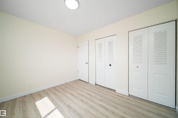 Neutral wall paint, wood-finish flooring, two sets of bi-fold louvered closet doors, and a flush-mount ceiling light - 