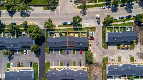Aerial perspective highlighting a multi-unit property with a dark shingle roof, individual patio spaces, and adjacent paved parking - 11432 139 Avenue Nw, Edmonton, AB - Outdoor With View