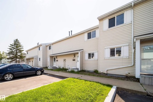 Townhome exterior featuring light-toned horizontal siding, white window trim, and white shutters - 11432 139 Avenue Nw, Edmonton, AB - Outdoor