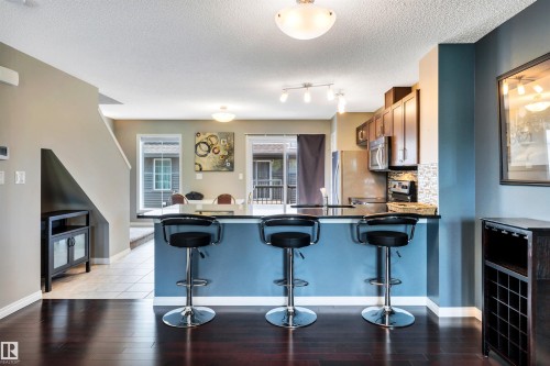 Open concept kitchen featuring a breakfast bar with a dark countertop and blue base - 571 Orchards Boulevard Sw, Edmonton, AB - Indoor Photo Showing Kitchen