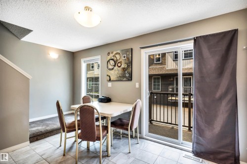 Dining area featuring tiled flooring, a sliding glass patio door, and a built-in wall sconce - 571 Orchards Boulevard Sw, Edmonton, AB - Indoor Photo Showing Dining Room