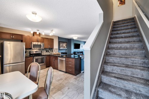 Carpeted staircase with white trim, leading to upper level - 571 Orchards Boulevard Sw, Edmonton, AB - Indoor Photo Showing Kitchen