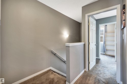 Carpeted hallway with neutral wall paint and white trim - 571 Orchards Boulevard Sw, Edmonton, AB - Indoor Photo Showing Other Room