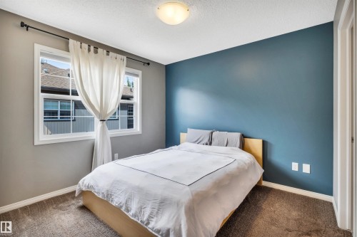 Bedroom featuring a bold accent wall, neutral carpeting, and a flush mount ceiling light - 571 Orchards Boulevard Sw, Edmonton, AB - Indoor Photo Showing Bedroom