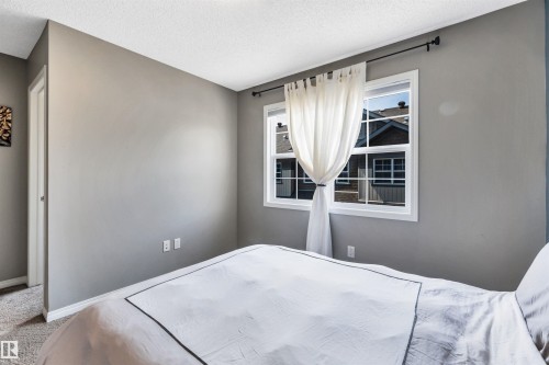 Bedroom featuring light gray walls, white trim, and a double-pane window with a black curtain rod - 571 Orchards Boulevard Sw, Edmonton, AB - Indoor Photo Showing Bedroom